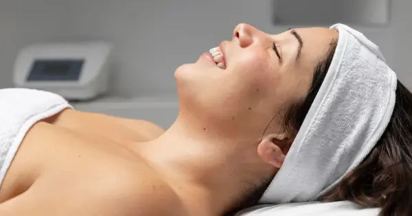 Profissional aplicando tratamento facial em uma cliente deitada na maca