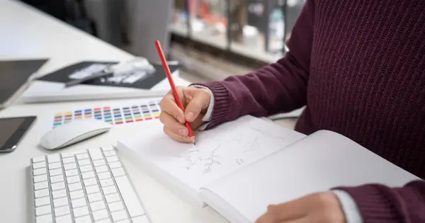 Designer desenhando um logotipo à mão em um caderno de rascunho