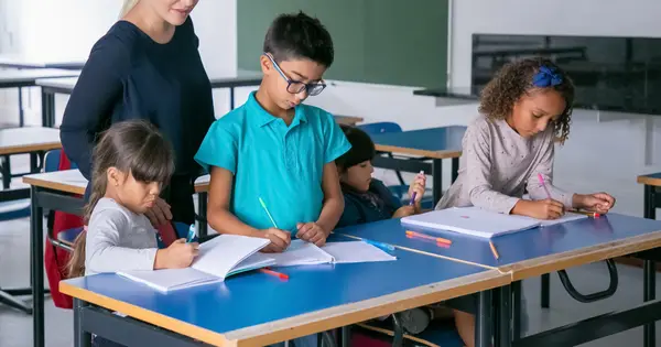 Professora acompanhando crianças em atividade na sala de aula